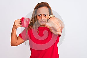 Middle age mature woman drinking a cup of hot coffee over isolated background pointing with finger to the camera and to you, hand