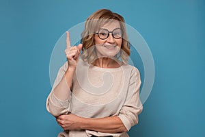 Middle age mature woman pointing finger up with successful idea.