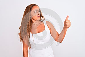 Middle age mature woman standing over white  background Looking proud, smiling doing thumbs up gesture to the side