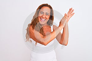 Middle age mature woman standing over white isolated background clapping and applauding happy and joyful, smiling proud hands