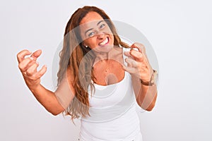 Middle age mature woman standing over white isolated background Shouting frustrated with rage, hands trying to strangle, yelling