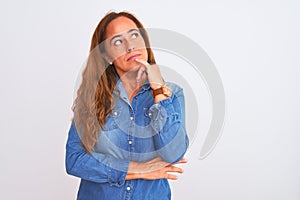 Middle age mature woman wearing denim jacket standing over white  background with hand on chin thinking about question,