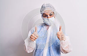 Middle age nurse woman wearing protection coronavirus equipment over white background success sign doing positive gesture with