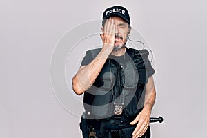 Middle age policeman wearing police uniform and bulletproof vest over white background surprised with hand on head for mistake,