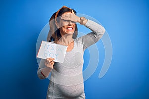 Middle age pregnant woman expecting baby boy over blue background stressed with hand on head, shocked with shame and surprise