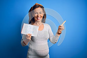 Middle age pregnant woman expecting baby boy over blue background very happy pointing with hand and finger to the side