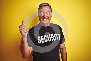 Middle age safeguard man wearing security uniform over isolated yellow background happy with big smile doing ok sign, thumb up