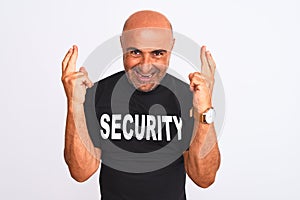 Middle age safeguard man wearing security uniform standing over isolated white background gesturing finger crossed smiling with