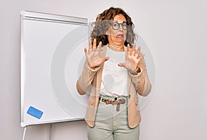 Middle age senior business woman standing on seminar presentation by magnectic blackboard afraid and terrified with fear