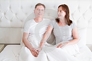 Middle age senior couple in bed. Template and blank t shirt. Front view. Healthy relationships. Copy space.