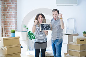 Middle age senior couple holding blackboard moving to a new home annoyed and frustrated shouting with anger, crazy and yelling