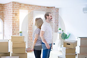 Middle age senior couple moving to a new home with boxes around looking to side, relax profile pose with natural face with