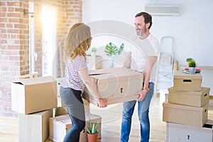 Middle age senior couple moving to a new house, holding cardboard boxing smiling happy in love with apartmant