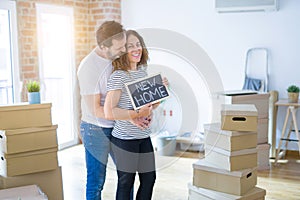 Middle age senior couple moving to a new house, smiling happy in love with apartmant holding a blackboard with new home text