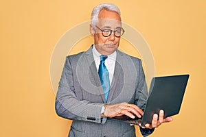 Middle age senior grey-haired business man wearing glasses working using computer laptop with a confident expression on smart face