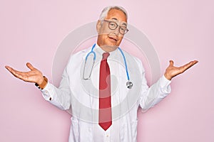 Middle age senior grey-haired doctor man wearing stethoscope and professional medical coat clueless and confused expression with