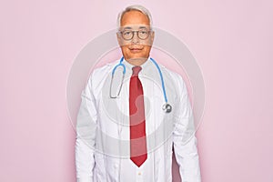 Middle age senior grey-haired doctor man wearing stethoscope and professional medical coat Relaxed with serious expression on face