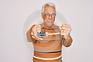 Middle age senior grey-haired man using tv remote control watching television annoyed and frustrated shouting with anger, crazy