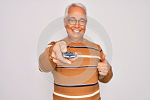 Middle age senior grey-haired man using tv remote control watching television happy with big smile doing ok sign, thumb up with