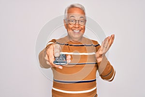 Middle age senior grey-haired man using tv remote control watching television very happy and excited, winner expression