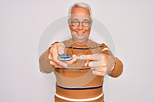 Middle age senior grey-haired man using tv remote control watching television very happy pointing with hand and finger