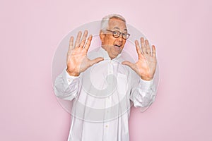 Middle age senior grey-haired man wearing glasses and business shirt over pink background afraid and terrified with fear