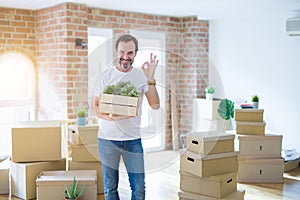 Middle age senior man moving to a new house packing cardboard boxes doing ok sign with fingers, excellent symbol