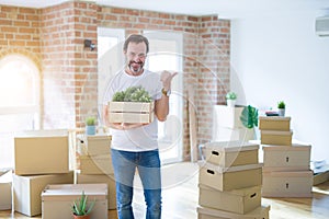 Middle age senior man moving to a new house packing cardboard boxes pointing and showing with thumb up to the side with happy face