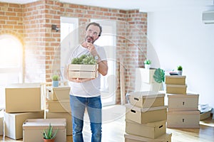 Middle age senior man moving to a new house packing cardboard boxes serious face thinking about question, very confused idea