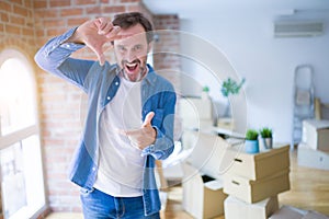 Middle age senior man moving to a new house packing cardboard boxes smiling making frame with hands and fingers with happy face