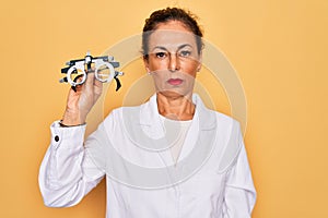 Middle age senior oculist woman holding optometrical glasses for vision correction with a confident expression on smart face