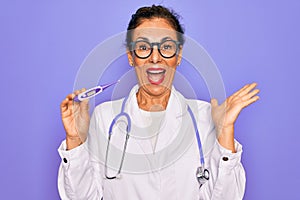 Middle age senior professional doctor woman holding medical thermometer very happy and excited, winner expression celebrating