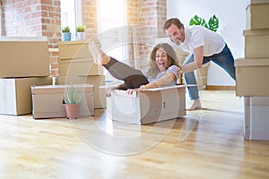 Middle age senior romantic couple having fun riding inside of cardboard, excited and smiling happy for moving to a new home