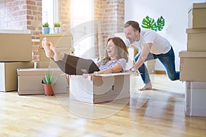 Middle age senior romantic couple having fun riding inside of cardboard, excited and smiling happy for moving to a new home