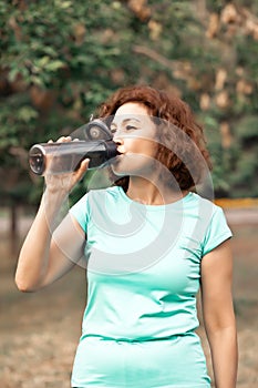 Middle age senior runner woman drinking bottled water after fitness exercise outdoors