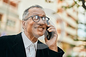 Middle age southeast asian man smiling speaking on the phone at the city