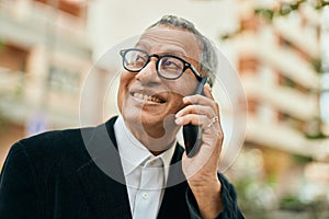 Middle age southeast asian man smiling speaking on the phone at the city