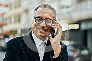 Middle age southeast asian man smiling speaking on the phone at the city