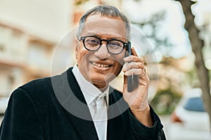 Middle age southeast asian man smiling speaking on the phone at the city