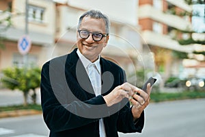 Middle age southeast asian man smiling using smartphone at the city