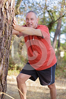 middle-age sportsman warming up and stretching outdoors