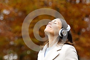 Middle age woman breathing fresh air with headphones in autumn