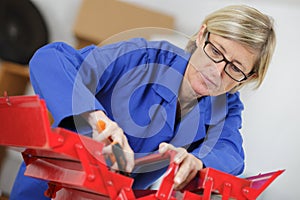 Middle-age woman in coveralls doing repairs with tool-box