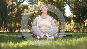 Middle age woman deeply breathing and meditating sitting in lotus position