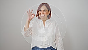 Middle age woman doing ok gesture smiling over isolated white background