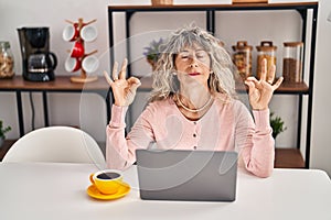 Middle age woman doing yoga exercise sitting on table at home