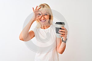 Middle age woman drinking glass of take away coffee standing over isolated white background with happy face smiling doing ok sign