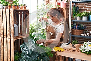 Middle age woman florist using difusser working at flower shop