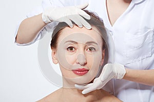 Middle age woman getting spa treatment. Face massage. Anti aging botox and collagen. Plastic surgery concept with doctor hands iso