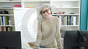 Middle age woman with grey hair teacher smiling confident standing at university classroom